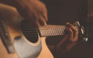 A person playing a guitar after doing some hand exercises.