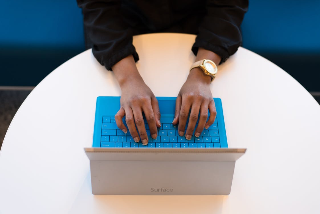 A woman wearing a watch and typing on a laptop