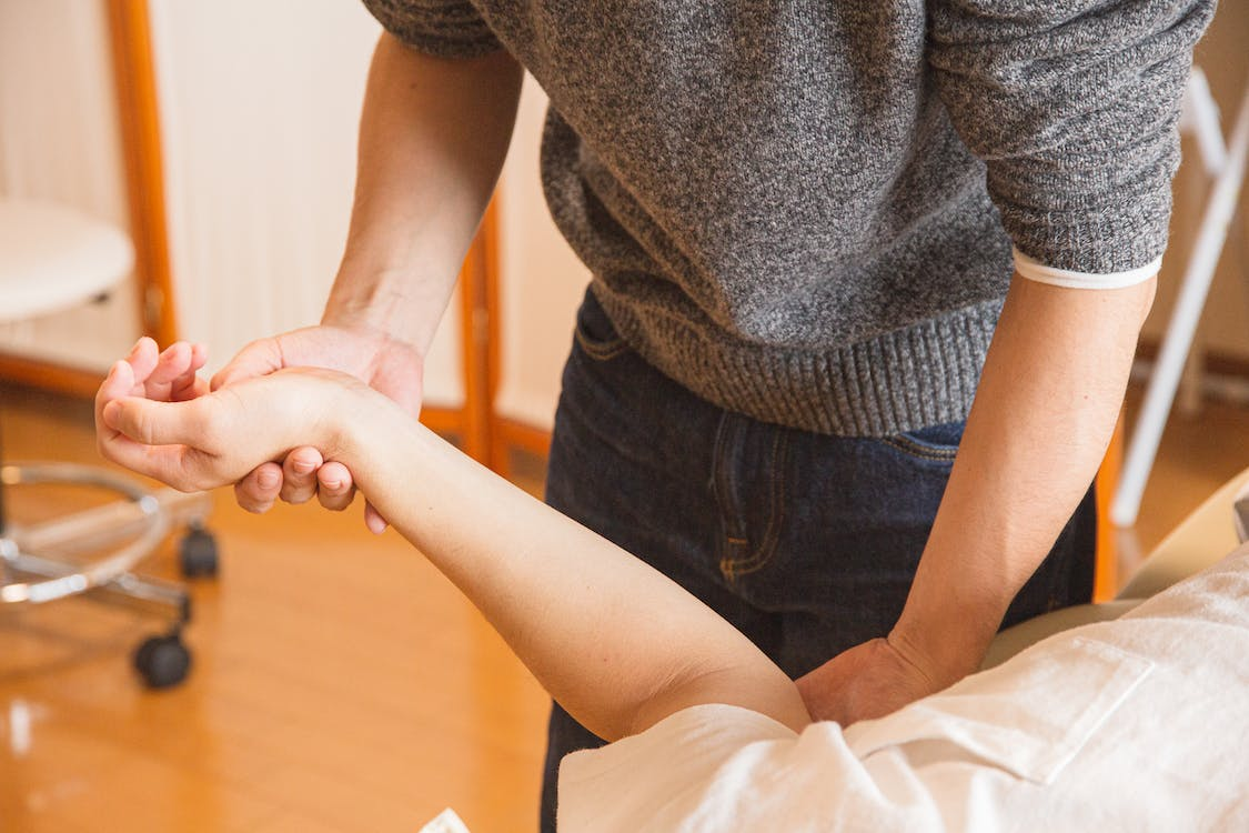 A chiropractor massaging the hand of a patient